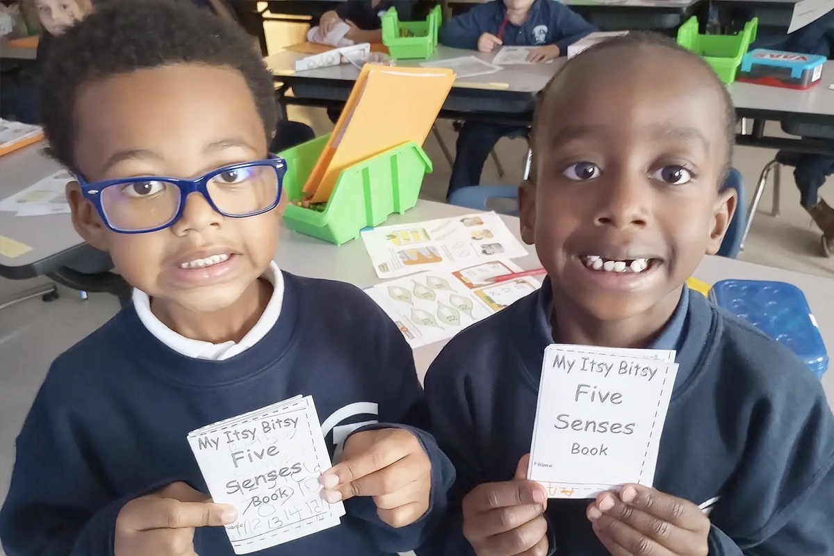 A pair of kindergarteners pose with their five senses booklets.